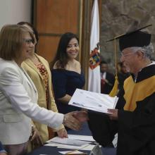 Egresado recibiendo reconocimiento por parte de la rectora