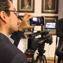 Periodista grabando con cámara profesional y celular