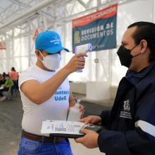 Persona tomando la temperatura a personal universitario