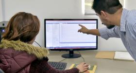 Profesor y estudiante frente a una computadora