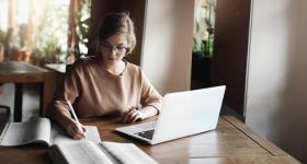 Estudiante frente a computadora, tomando notas