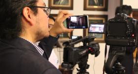 Periodista grabando con cámara profesional y celular