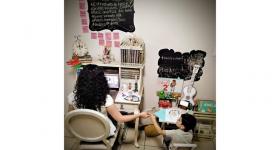 Mamá trabajando frente a computadora con su hijo a un costado con material escolar
