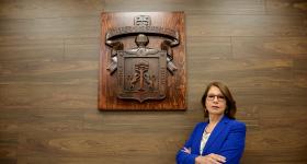 Rectora Maria Esther Avelar, delante del logo de la Universidad de Guadalajara